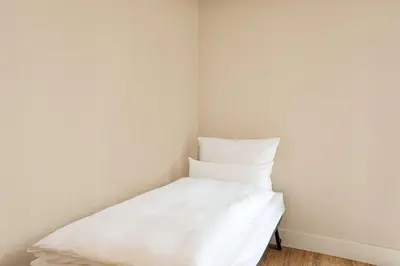 a white bed in a corner of a room at NH Amsterdam Noord in Amsterdam