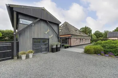 a barn style house with a driveway and a building at Kapberg 'Om de Noord' in Warmenhuizen