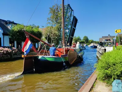 a boat with a flag is docked on a river at Park De Driesprong in Nieuwveen
