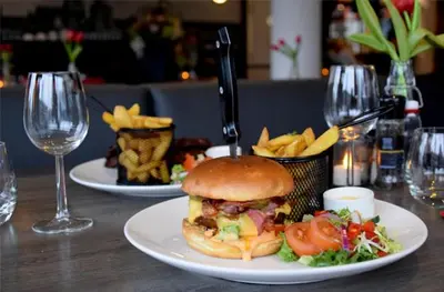 a plate with a sandwich and french fries on a table at Bastion Hotel Leiden Voorschoten in Leiden
