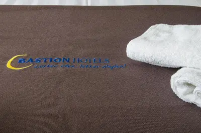 a white towel on a table with aiction hotels sign at Bastion Hotel Utrecht in Utrecht