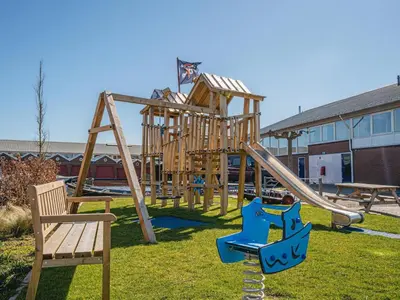 a park with a wooden playground with a slide at Apartment in Waterpark in Uitgeest in Uitgeest