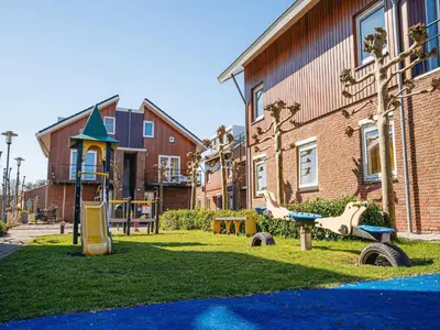 a playground in a yard next to a building at Apartment in Waterpark with Private Jetty in Uitgeest