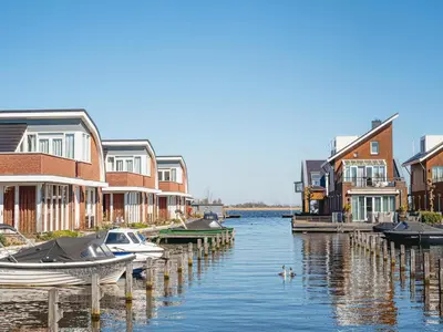 a group of boats docked next to houses on the water at Waterside Escape with Easy Access in Uitgeest