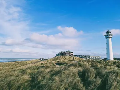 a lighthouse sitting on top of a hill next to the ocean at Bodhi Beach House in Egmond aan Zee