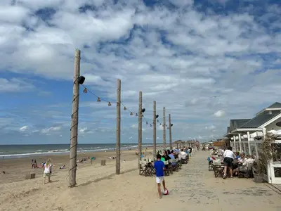 a group of people sitting on the beach at Holiday Home Putter Comfort by Interhome in Noordwijk