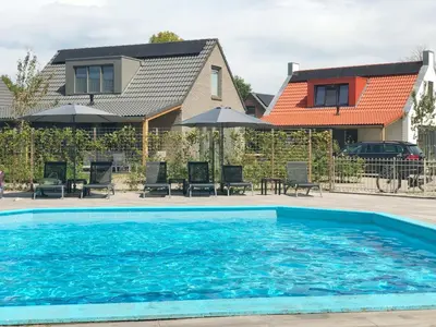 a swimming pool in front of a house at Bungalow 71 op Recreatiepark De Wielen in Sint Maarten