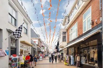 a group of people walking down a shopping street with flags at Loft 29 in Zandvoort