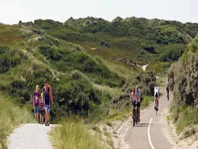 a group of people riding bikes down a road at Holiday Home in Noordwijk near the Beach in Noordwijk aan Zee