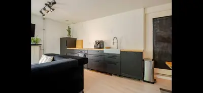 a living room with a couch and a kitchen at Quiet Garden Room Amsterdam West - by Peter in Amsterdam