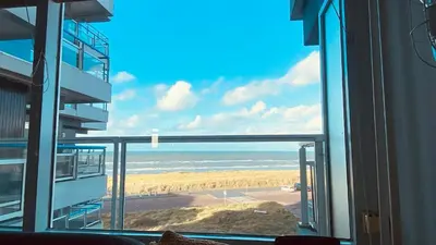 a view of the beach from a window of a building at Sterflat 119 in Egmond aan Zee