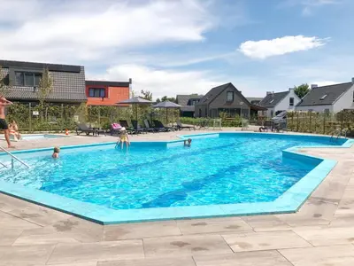 a swimming pool with people in the water at Bungalow 68 op Recreatiepark De Wielen in Sint Maarten