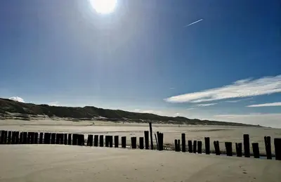 a beach with a wooden fence in the sand at Villa de Duinfazant in Bergen aan Zee