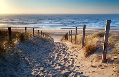 a sandy beach with a fence and the ocean at Solaris in Egmond aan den Hoef