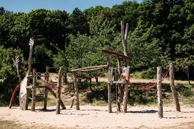a wooden playground on the beach with trees in the background at Stayokay Hostel Noordwijk in Noordwijk