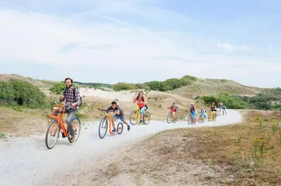 a group of people riding bikes on a dirt road at Stayokay Hostel Noordwijk in Noordwijk