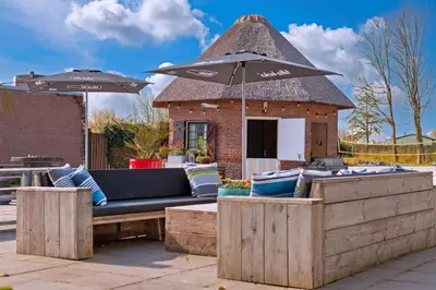 a patio with a bench and an umbrella at Stayokay Hostel Noordwijk in Noordwijk