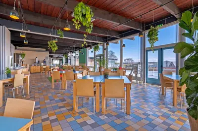 a restaurant with tables and chairs and windows at Stayokay Hostel Noordwijk in Noordwijk