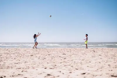 two people playing with a frisbee on the beach at Stayokay Hostel Noordwijk in Noordwijk