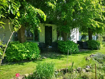a house with a porch with trees and grass at Sweet Tiny House in Westbeemster