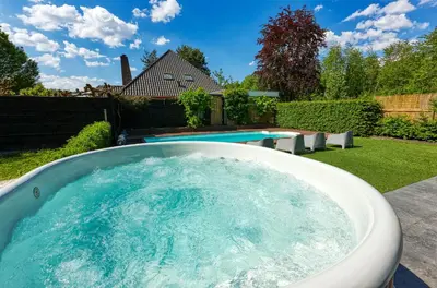 a hot tub in a backyard with a pool at Rode Tiny House met zwembad in Zeewolde
