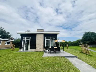 a small house with a table and chairs in the yard at Bungalowpark de Horn - Floresta 213 in Dirkshorn