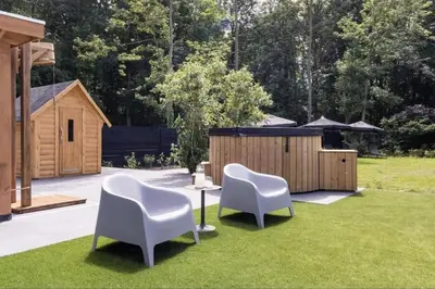 a yard with two white chairs and a table in the grass at Yellow Tiny House with shared pool in Zeewolde
