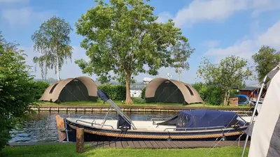 a small boat with two tents on the water at Glamping at the water, close to Amsterdam in Aalsmeer