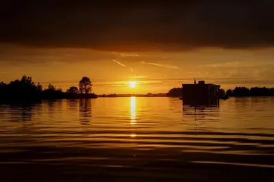 a sunset over a body of water with the sun setting at Houseboat Tomio near Amsterdam in Monnickendam