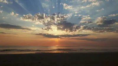 a sunset on the beach with the ocean and clouds at Vakantiewoning MV8 in Egmond-Binnen