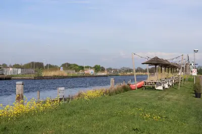 a dock with tables and a boat on the water at Safari Lodges Premium in Nieuwe Wetering