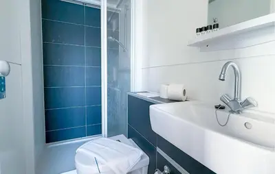 a bathroom with a sink and a toilet and blue tiles at Trancoso in Naarden