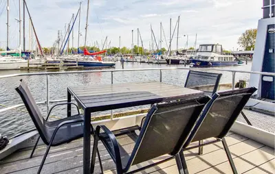 a table and chairs on a dock with boats in the water at Sydney in Naarden