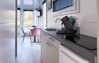 a kitchen with a sink and a table with chairs at Sydney in Naarden