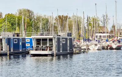 a house boat docked at a marina with boats at Monaco in Naarden