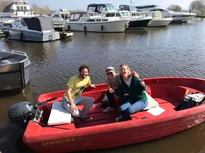 three people sitting on a red boat in the water at Design huisje vrij in het groen in IJsselstein