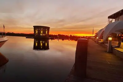 a sunset over a body of water with a dock at Design huisje vrij in het groen in IJsselstein