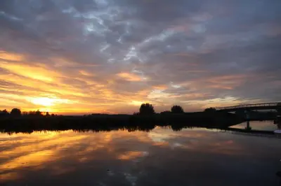 a sunset over a body of water with a bridge at Dobberhuisje in IJsselstein