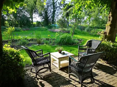 a patio with three chairs and a table in a yard at Modern Cozy Asian Style bedroom with Kingsize Spa bath in Westbeemster