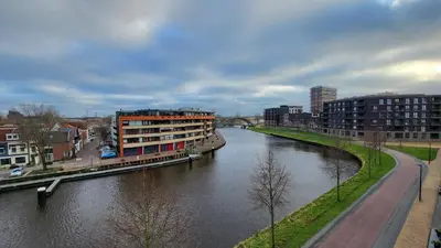 a river in a city with buildings and a bridge at B&B Kopwest 1 in Purmerend