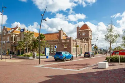a blue car parked in front of a building with a clock tower at Reumann Holiday Apartments De Schelp 12 in Zandvoort