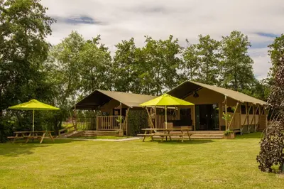 a building with tables and umbrellas in a yard at Zorgcamping De Ruif De Peppelhoeve in Stoutenburg