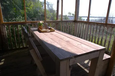 a wooden table on a porch with a plant on it at Glampingtent de Deiling, de Woudhaven in De Woude