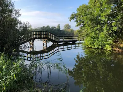 a bridge over a river with a reflection in the water at Chalet 7a op Recreatiepark De Wielen in Sint Maarten