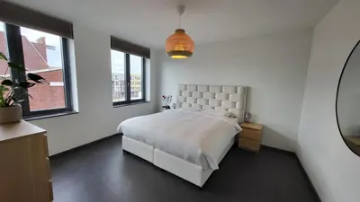 a white bedroom with a large bed and windows at B&B Kopwest 8 personen in Purmerend
