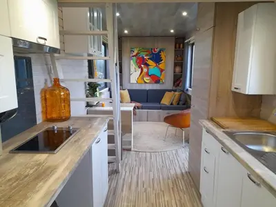 a kitchen with a sink and a living room at Tiny House Egmond in Egmond aan den Hoef