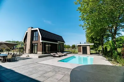 a home with a swimming pool and a house at Vakantierijk Waarland in Waarland