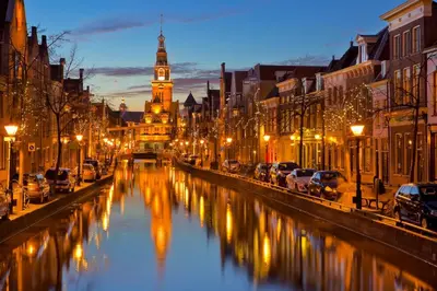 a city street with a river with a clock tower at Authentic townhouse Alkmaar in Alkmaar