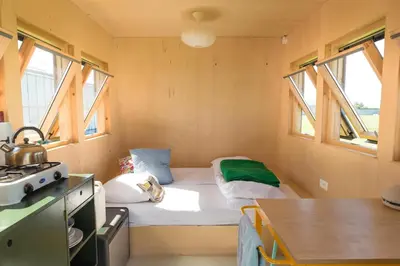a small room with a bed and two windows at Hihahut De Vogelaar in Oud-Ade