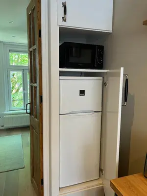 a microwave on top of a refrigerator in a kitchen at Museum district, beautiful renovated house in Amsterdam